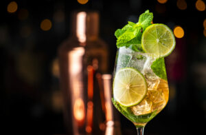 Ein erfrischender Hugo Spritz Cocktail mit Limettenscheiben, Minze und Eiswürfeln, bereit zum Genuss auf einer Veranstaltung von GustoFino. Idee bei Cocktails für Hochzeit.