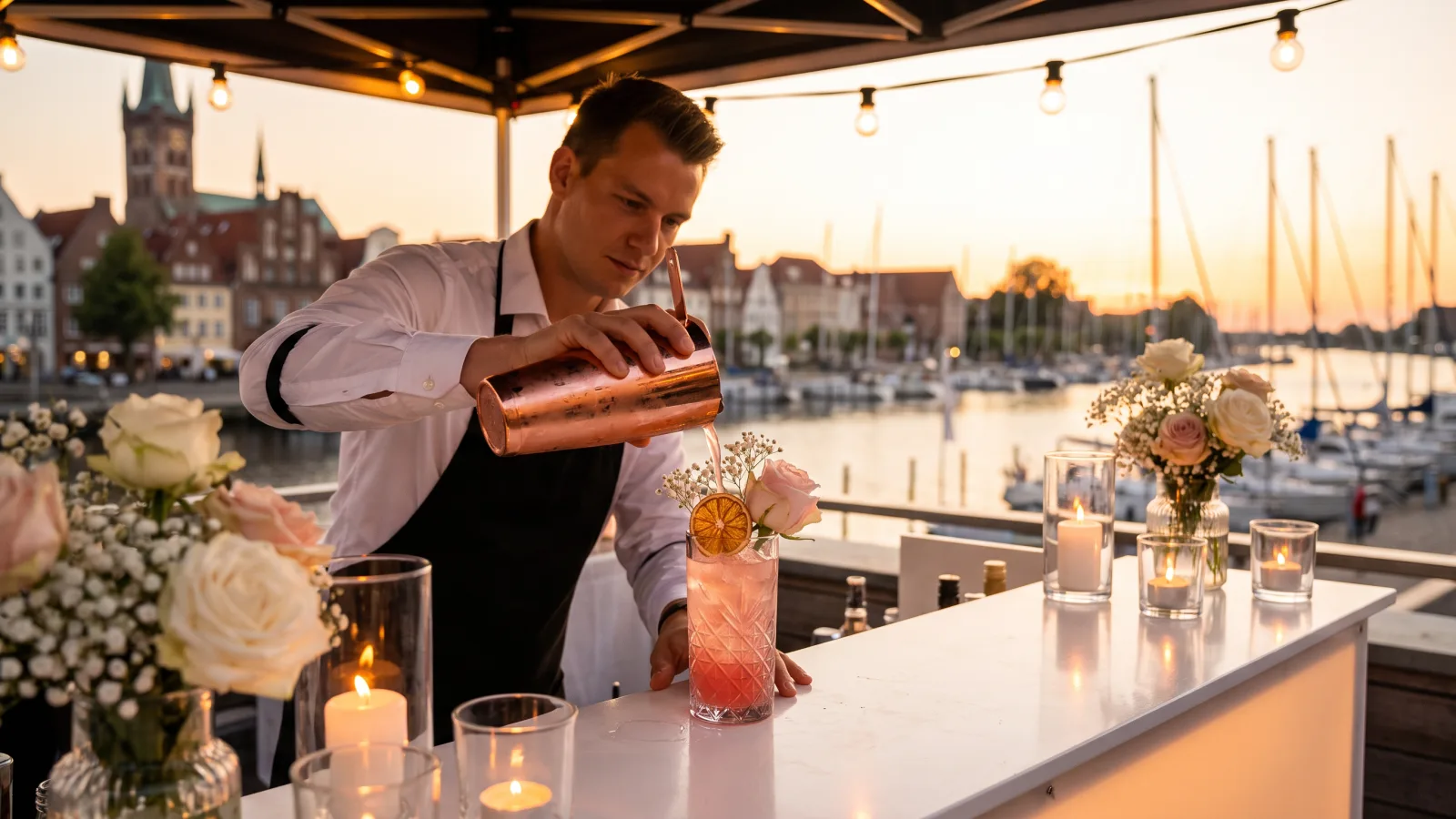 Ein Barkeeper mixt Cocktails an einer stilvollen Outdoor-Eventlocation Lübeck am Hafen bei Sonnenuntergang.